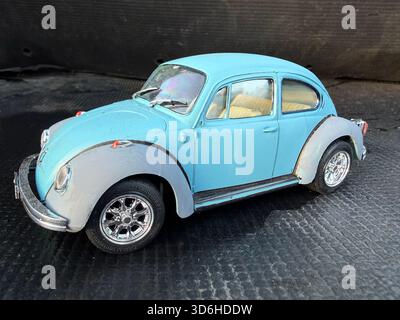 Nahaufnahme eines hellblauen Vintage-Spielzeugwagenmodells eines klassischen Volkswagen Käfers Typ 1 auf strukturierter dunkler Oberfläche Stockfoto
