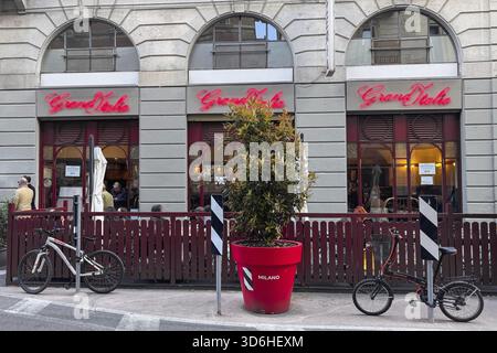 Mailand, Italien - 07. April 2025: Restaurant Gran Italia mit rotem Neonschild und Terrasse. Fahrräder und rote Pflanzgefäße auf der Straße Stockfoto