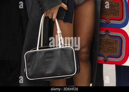Paris, Frankreich - 11. März 2025: MIU Miu rechteckige schwarze Ledertasche mit weißem Besatz, goldfarbene Beschläge. Details zum Street-Style-Outfit Stockfoto