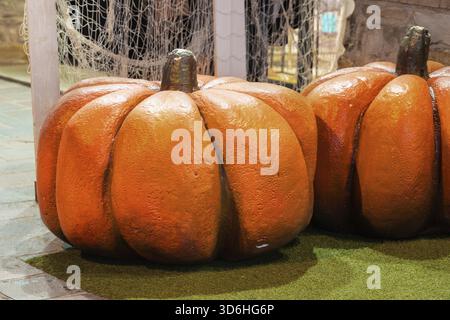 Künstliche orangefarbene Kürbisse in der Inneneinrichtung. Herbstpräsentation, Halloween Stockfoto