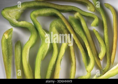 Grüne Paprika Scheibe oder Schnitt Textur. Kreative Gestaltung der Pfefferstücke. Set von geschnittenem Gemüse auf weißem Teller. Food Art. Abstrakt minimal kompostiert Stockfoto