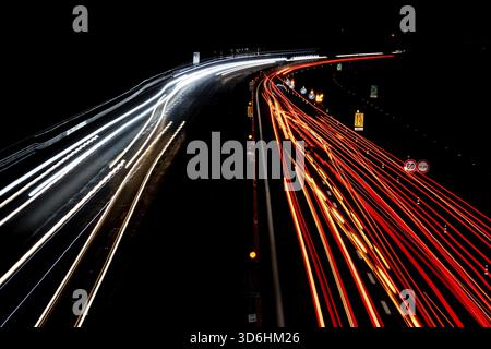 Abstraktes Bild von Nachtverkehrsampeln auf der Straße. Leichte Autofahrten bei Nacht auf kurvenreichen Asphaltstraßen. Langzeitbelichtung zeigt Bewegungen von Autos aus bridg Stockfoto