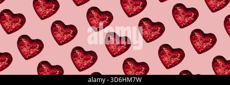 Weihnachts- oder Valentinskomposition aus glühender roter Herzdeko und Glitzer auf rosa Oberfläche. Frohe weihnachten und glückliches Neues Jahr 2021, glücklich Stockfoto