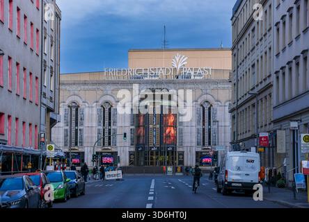 Abendlicher Blick auf den Friedrichstadt-Palast in Berlin, Deutschland, mit der beleuchteten Theaterfassade, die von umliegenden Gebäuden eingerahmt wird. Stockfoto