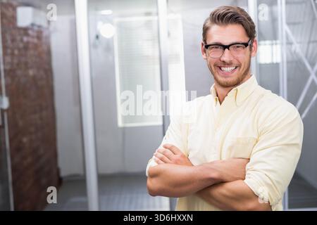 Mann, der im Büro lächelnd die Arme gekreuzt hat, trug Brille und gelbes Hemd, Kopierraum. Geschäftsmann, Profi, Arbeitsplatz, offener Plan, Stockfoto