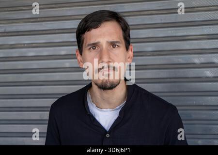 Mann mit Bart und Schnurrbart, der einen besorgten Gesichtsausdruck zeigt, vor einem metallenen Rolltor-Hintergrund Stockfoto