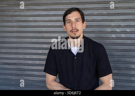 Junger Mann, der mit ernstem Ausdruck in die Kamera starrt Stockfoto