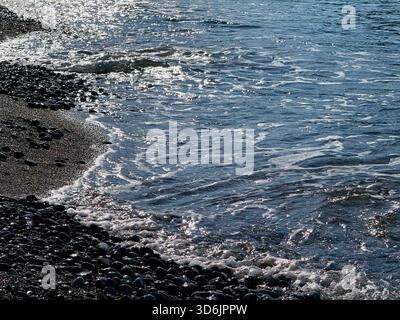 Sanfte Wellen am Kiesstrand am Abend Stockfoto