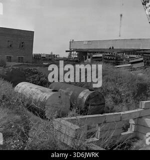 Slawjansk, Ukraine, UdSSR - November 1978: Industrielles Archivfoto der Baustelle der neuen Brotfabrik. Zwei große Metallzisternen liegen in einer ausgehobenen Grube, die einbaufertig ist. Im Hintergrund befinden sich Arbeiter auf dem Dach des Hauptproduktionsgebäudes. Links steht ein gemauertes Nebengebäude. Das Schwarzweiß-Bild erfasst die Entwicklung der technischen Infrastruktur und den Umfang des industriellen Bauens in der Donezker Region während der friedlichen Sowjetzeit. Stockfoto