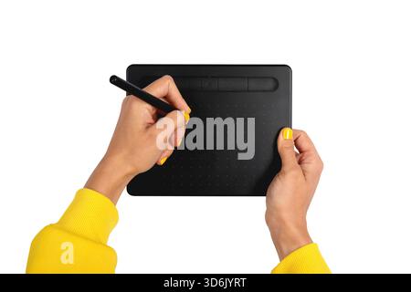 Nahaufnahme der Hände mit gelben Ärmeln und passendem nagellack mit einer schwarzen digitalen Zeichentablette mit Stift auf weißem Hintergrund. Stockfoto