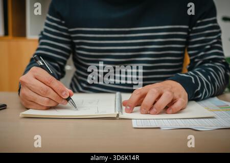 Nahaufnahme der Hand mit Stift und Notebook im Home Office Stockfoto