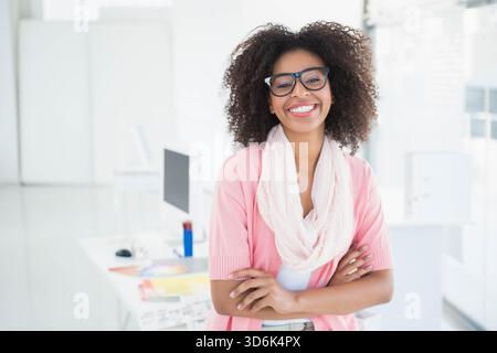 Afroamerikanerin, die am Schreibtisch steht und einen rosa Strickschal neben einem Computer mit Farbmustern trägt. Professionell, weiblich, geschäftlich, Büro, Monitor, PA Stockfoto