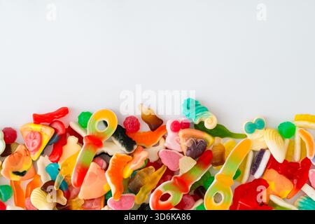 Kreativer Hintergrund aus verschiedenen gummiartigen Bonbons mit Kopierraum. Minimales trendiges Gummikonzept. Gelee-Süßigkeiten-Ästhetik. Farbenfrohe flache Lagen. Draufsicht Stockfoto