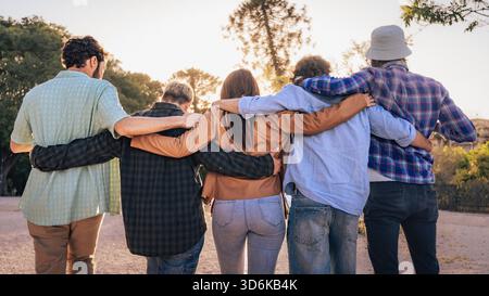 Verschiedene Gruppen von Freunden stehen zusammen im Freien, alle lächeln und tragen eine Sonnenbrille, legere Kleidung und wirken entspannt bei Tageslicht. Stockfoto