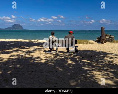 Black River, Mauritius, 28. Juli 2023 - zwei mauritische Männer sitzen auf einer Bank am Strand von La Preneuse Stockfoto