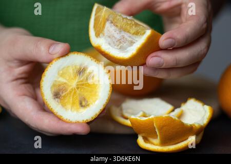 Nahaufnahme von weiblichen Händen, die schlecht schimmelige Orange halten Stockfoto