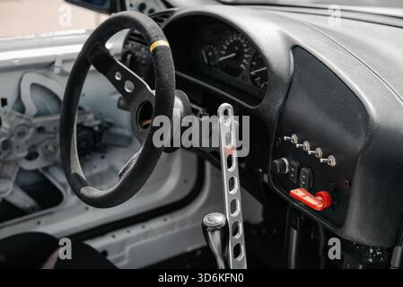 Innenraum des Rennwagens, Cockpit mit hellem Sonnenlicht. Nahaufnahme des Lenkrads und des Armaturenbretts in einem Driftfahrzeug. Stockfoto