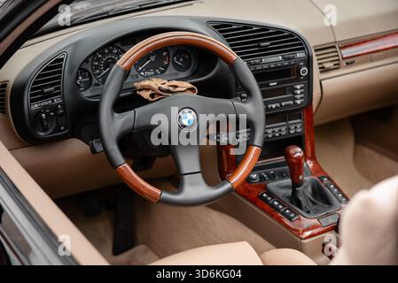 Innenraum des BMW E36 mit geöffnetem Dach. Cockpit eines deutschen Autos aus den 1990er Jahren mit beigefarbenem Leder und Holzverkleidung. Stockfoto