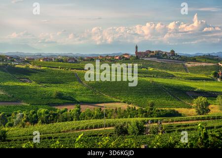 Pulsierender Blick auf den Sonnenuntergang über die terrassenförmig angelegten Weinberge der Region Langhe, Piemont, Italien. Das kleine Dorf und die Kirche von Santo Stefano Canetto Stockfoto