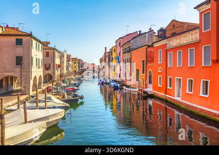 Lebhafter Blick auf den Vena Canal in Chioggia, bekannt als Little Venice. Traditionelle, farbenfrohe Häuser säumen das Wasser und eine Brücke ist in der Ferne sichtbar Stockfoto