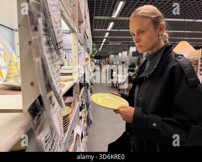 Frau, die im Laden Geschirr kauft Stockfoto