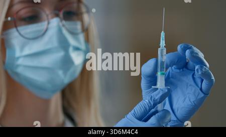 Close up Kaukasierin Arzt in medizinischer Gesichtsmaske halten Spritze Injektion Impfung in Klinik Krankenschwester weibliches Mädchen Vorbereitung auf Impfmittel Stockfoto