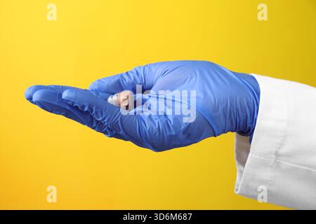 Arzt mit Hörgerät auf gelbem Hintergrund, Nahaufnahme Stockfoto