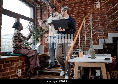 Multiethnische junge Erwachsene, die Ideen sammeln, während sie auf der Bürotreppe stehen Stockfoto