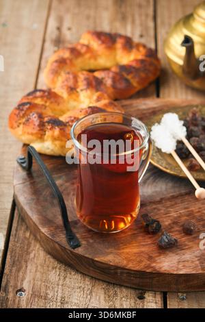 Türkischer schwarzer Tee. Eine Glasschale türkischer schwarzer Tee und knuspriger türkischer traditioneller Bagel auf altem Rustick-Hintergrund. Frühstücksgebäck-Konzept. Traditionelles türkisches Heißgetränk. Stockfoto