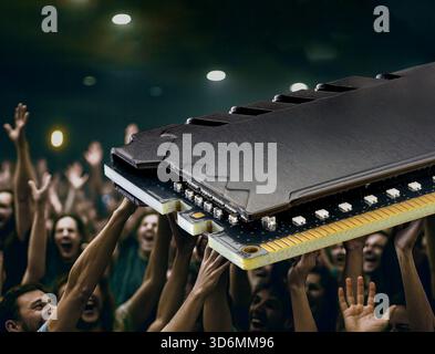 Eine große Gruppe aufgeregter Menschen hebt die Hände mit einem großen RAM-Modul darüber Stockfoto