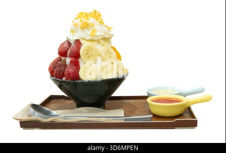 Ein Set koreanischer Bingsu in einer kleinen schwarzen Schüssel mit mehreren Früchten und roter Sauce mit süßer Kondensmilch in Mini-Plastikschüsseln in braunem Tablett Stockfoto