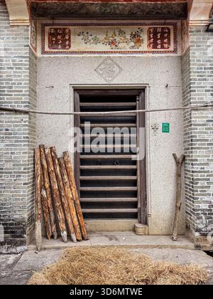 Traditioneller Eingang, Zili Village. Historische Tür mit Holzlatten, dekorativem Fries und traditionellen Gegenständen an der Basis. Kaiping, Chin Stockfoto