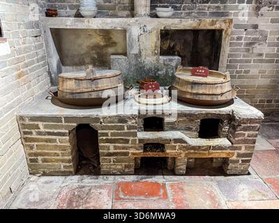 Alte Küchennachbildung mit traditionellen Backsteinöfen und großen Woks mit Holzdeckeln, entworfen zum Kochen mit brennendem Holz. Befindet sich in Zili Villag Stockfoto