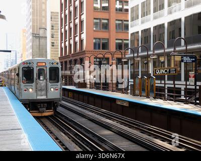Chicago, IL - 16. September 2025: Nahaufnahme eines CTA-Zuges, der sich dem Bahnsteig Quincy nähert, umrahmt von urbaner Architektur. Stockfoto