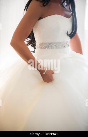 Braut im trägerlosen Kleid mit Perlenbesatz an der Taille Stockfoto