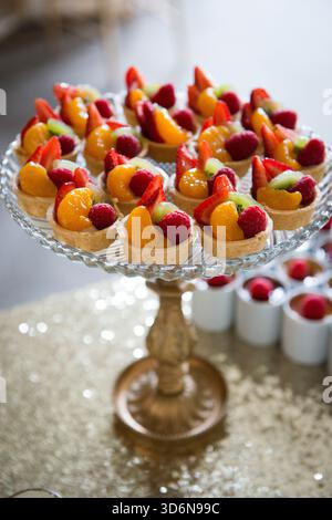 Farbenfrohe Mini-Obsttörtchen auf elegantem Dessertstand Stockfoto