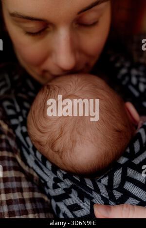 Mutter hält das schlafende Neugeborene zärtlich in der Nähe Stockfoto