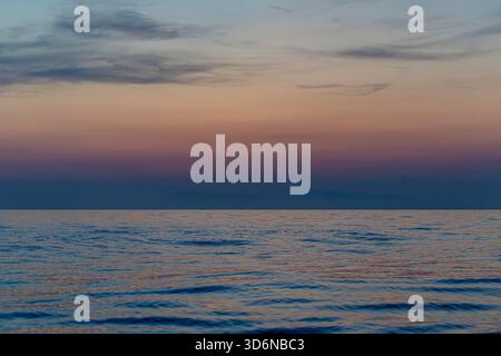 Sanfter Sonnenuntergang in Pastellfarben über einem ruhigen offenen Meer Stockfoto