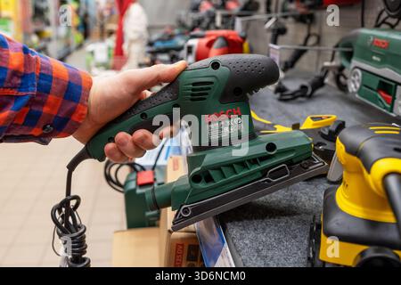 Bosch Schwingschleifer. Ein Mann in einem Eisenwarengeschäft wählt einen neuen Bosch Schwingschleifer. Schwingschleifer-Werkzeug in Handnahmebildung. Minsk, Weißrussland, 2022 Stockfoto
