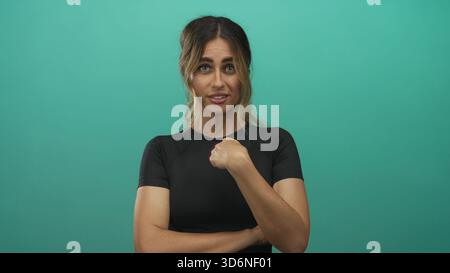 Junge blonde Frau zeigt den Finger in einem grünen Fotostudio nach oben; Selbstvertrauen Verspieltheit Motivation Stärkung. Stockfoto