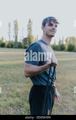 Konzentrierter junger Mann, der mit Widerstandsband im Udine Park trainiert. Stockfoto