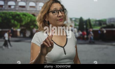 Frau zeigt mit dem Finger auf die Kamera im kolosseum Gebäude im Freien, Touristenattraktion in der Nähe römischer Ruinen; Warnbehörde. Stockfoto