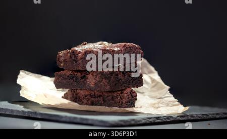 Ein Stapel köstlicher Schokoladen-Brownies auf dunklem Hintergrund Stockfoto