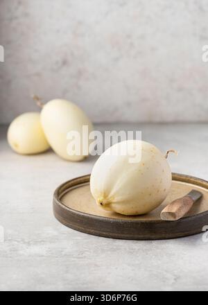 Frische „Kristallapfel“-Gurke (Cucumis sativus) auf einer rustikalen Keramikplatte mit ganzen Früchten im Hintergrund. Stockfoto
