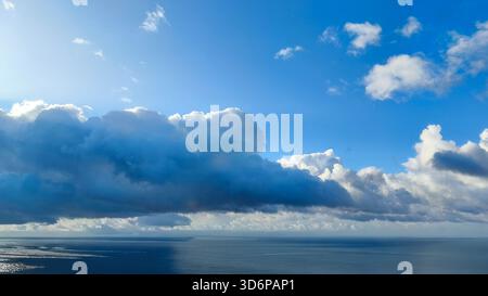 Die Weite des Ozeans erstreckt sich unter einer atemberaubenden Wolkendecke und blauem Himmel Stockfoto