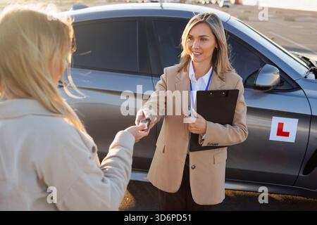 Fahrlehrer übergibt dem Schüler vor dem Unterricht Autoschlüssel Stockfoto