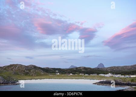 Blick auf die Küste mit rosa Wolken bei Sonnenuntergang, ruhigem Meer und malerischen Hügeln im Hintergrund, Achmelvich Beach, Sutherland, Schottland, Großbritannien Stockfoto