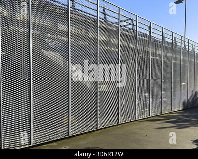 Eine vertikale, hochwinklige Aufnahme der Fassade eines modernen Parkhauses mit langen, hohen Paneelen aus diamantförmigem weißem Streckmetallgitter (Contra) Stockfoto