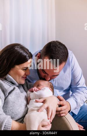 Eltern küssen und halten ihr Neugeborenes liebevoll fest Stockfoto