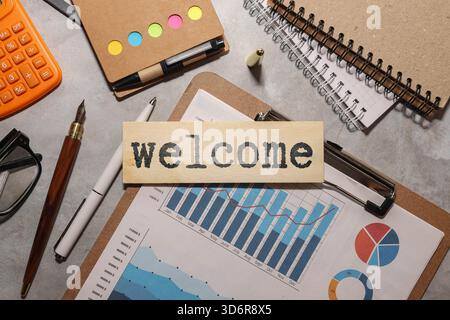 Geschäftskonzept. Begrüßungstext auf einer weißen Karte neben dem Visitenkartenhalter in schwarz auf orangem Hintergrund Stockfoto